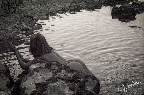 Femme allongée sur un rocher au bord d'une rivière