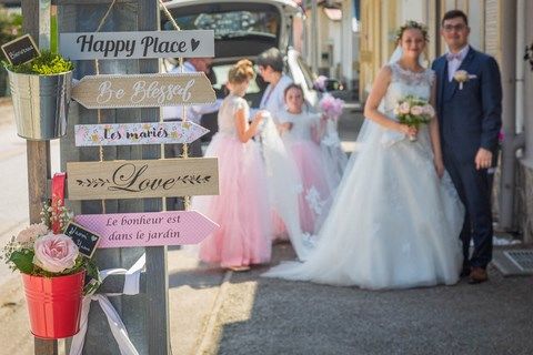 les mariés en arrière plan derrière un piquet avec des pancartes bonheur et amour